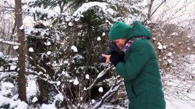 Kışın elinde kamera olan genç bir kadının portresi. Kız kışın fotoğraflarını çekiyor. Karlı bir parkta kamerası olan mutlu genç bir kadın.. 