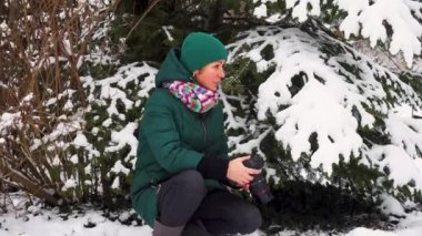 Kışın elinde kamera olan genç bir kadının portresi. Kız kışın fotoğraflarını çekiyor. Karlı bir parkta kamerası olan mutlu genç bir kadın.. 