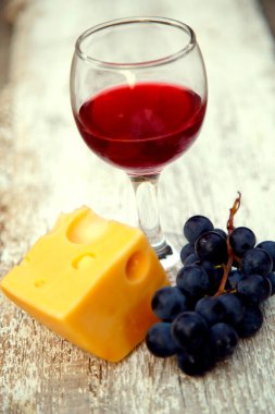 Üzüm ve peynirin içinde bir kadeh kırmızı şarap. Bahçede kırmızı şarap, peynir ve üzüm karışımı.. 