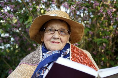 Yaşlı bir kadın parkta bir bankta İncil okuyor. Pansiyondaki yaşlı bir kadın Tanrı 'nın sözlerini okuyor. Yaşlılık, inanç, din kavramı.