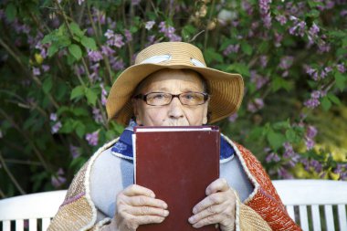 Yaşlı bir kadın parkta bir bankta İncil okuyor. Pansiyondaki yaşlı bir kadın Tanrı 'nın sözlerini okuyor. Yaşlılık, inanç, din kavramı.