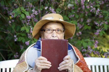 Yaşlı bir kadın parkta bir bankta İncil okuyor. Pansiyondaki yaşlı bir kadın Tanrı 'nın sözlerini okuyor. Yaşlılık, inanç, din kavramı.