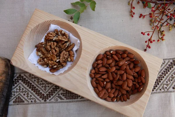 Masadaki ahşap tabakta kavrulmuş badem ve ceviz 