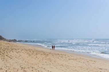 Okyanus kıyısında insanların dinlendiği bir sahil, tatil yeri. Dağlar, deniz ve dalgalar. Avrupa 'ya, Portekiz' e git. Praia de Vale Furado.