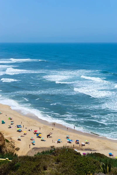 Okyanus kıyısında insanların dinlendiği bir sahil, tatil yeri. Dağlar, deniz ve dalgalar. Avrupa 'ya, Portekiz' e git. Praia de Vale Furado.