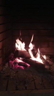 Parlak ve canlı bir ateş şöminede yanar, sıcak bir ışık yayar ve parlak alevler sergiler..