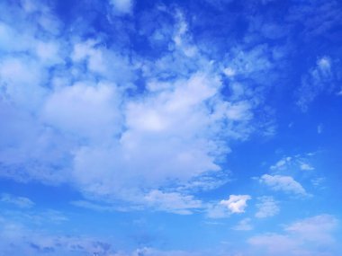 Açık mavi gökyüzü dokusu ve beyaz tüylü bulut doğa arkaplanı. Yazın gün ışığında güneş parlar, meteoroloji. Panoramik görüntüde yumuşak güneş ışığı. Cennet, barış konsepti ve kopyalama alanı. Huzurlu ve huzurlu bir atmosfer.