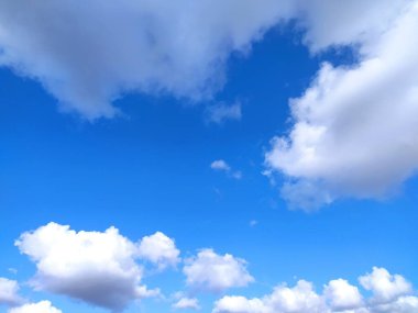 Açık mavi gökyüzü dokusu ve beyaz tüylü bulut doğa arkaplanı. Yazın gün ışığında güneş parlar, meteoroloji. Panoramik görüntüde yumuşak güneş ışığı. Cennet, barış konsepti ve kopyalama alanı. Huzurlu ve huzurlu bir atmosfer.