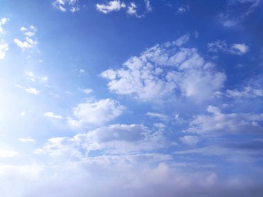 Açık mavi gökyüzü dokusu ve beyaz tüylü bulut doğa arkaplanı. Yazın gün ışığında güneş parlar, meteoroloji. Panoramik görüntüde yumuşak güneş ışığı. Cennet, barış konsepti ve kopyalama alanı. Huzurlu ve huzurlu bir atmosfer.