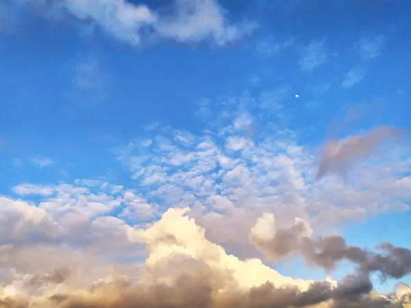 stock image The sun is setting, casting a warm glow over the clouds in the sky. The vibrant colors of the sunset are reflected in the clouds, creating a dramatic and beautiful scene.