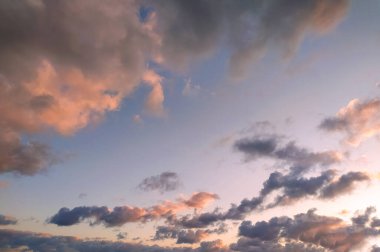 Güneş batıyor, gökyüzündeki bulutların üzerine ılık bir parıltı saçıyor. Gün batımının canlı renkleri bulutlara yansıyarak dramatik ve güzel bir sahne yaratıyor..