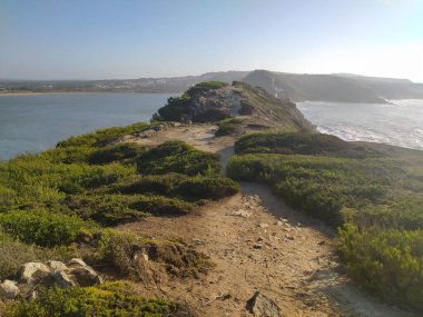Öğleden sonra dalgalar engebeli uçurumlara çarpar ve kıyı şeridi boyunca büyüleyici bir manzara yaratır. Güneş doğayı aydınlatır, doğal güzelliği arttırır..