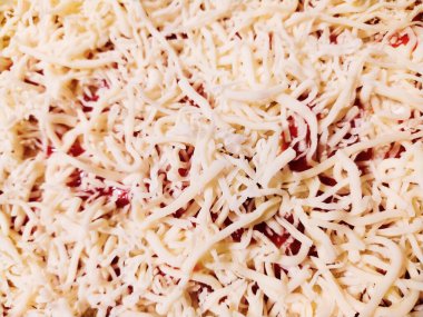 Yakın plan dilimlenmiş peynirin kırmızı sosun üzerine cömertçe katılmış hali. Yemek blogları, yemek tarifleri web siteleri ya da restoran menüleri için ideal. Lezzetli ve iştah açıcı bir görsel doku yaratır..