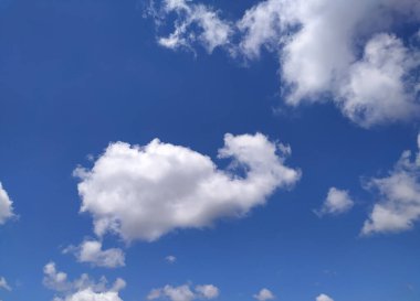 Açık mavi gökyüzü dokusu ve beyaz tüylü bulut doğa arkaplanı. Yazın gün ışığında güneş parlar, meteoroloji. Panoramik görüntüde yumuşak güneş ışığı. Cennet, barış konsepti ve kopyalama alanı. Huzurlu ve huzurlu bir atmosfer.