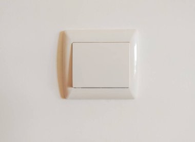 Beyaz bir duvardaki tek bir sönük beyaz ışık düğmesinin temiz, minimalist görüntüsü. İç tasarım, ev geliştirme ya da minimalist yaşam tarzı projeleri için mükemmel. Nötr renk paleti çok yönlülüğü sağlarName.