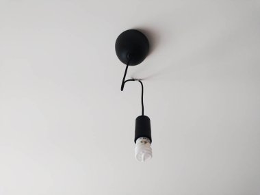 Gösterişli minimalist siyah kolye ışığı ve beyaz tavana asılı bir ampul. İç tasarım, ev dekorasyonu ve mimarlık projeleri için mükemmel. Temiz çizgiler ve basit estetik.