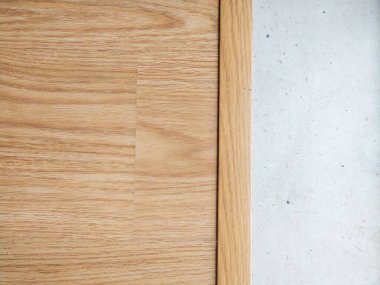 Hafif meşe ağacının temiz görüntüsü açık gri beton bir yüzey ile yan yana dikey ahşap süsleme ile ayrılmış..