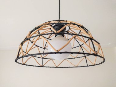 Modern geometrik dizaynlı şık kolye lambası. Doğal bej renginde rattan aksanı var. Parlak siyah tel çerçeveyle çok güzel tezat oluşturuyor..