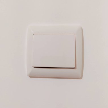 Tarafsız bir duvardaki beyaz ışık düğmesinin temiz, minimalist görüntüsü. İç tasarım, ev geliştirme ve minimalist yaşam tarzı projeleri için mükemmel. Herhangi bir tasarıma modern basitliğin dokunuşunu ekler.