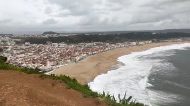 Sahilde kumlu bir sahil manzarası ve bulutlu bir gökyüzünün altında dalgalar. Seyahat, tatil, doğa ve deniz kenarında yaşayan kavramları çağrıştırıyor. Turizm reklamları için ideal.