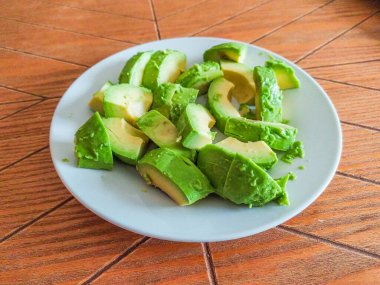 Taze avokado dilimleri tabakta, canlı yeşil ve yemeye hazır. Sağlıklı beslenme, yemek tarifleri ya da yemek blogu görselleri için mükemmel. Doğal ışıklandırmalı yüksek kalite resim.