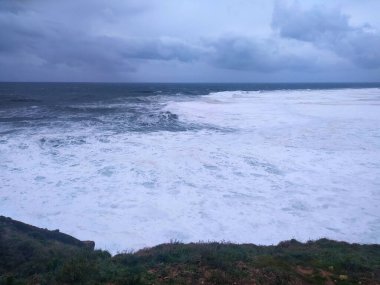 Güçlü dalgaların fırtınalı bir gökyüzü altında çarpıştığı dramatik deniz manzarası. Doğa kuvvetleri, esneklik ve çevresel zorlukları çağrıştırıyor. Özgeçmiş ya da yazı işleri için mükemmel.