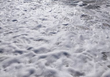 Kumlu sahil, yumuşak dalgaların parlak ve berrak bir gökyüzünün altında kıyıya ulaştığı sahil boyunca uzanır ve ziyaretçiler için huzurlu bir atmosfer yaratır..