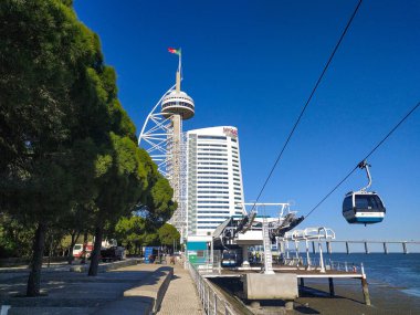 Modern teleferik sistemi olan güneşli şehir manzarası yüksek bir otelin ve ikonik gözlem kulesinin yanından süzülüyor. Seyahat, turizm, şehir keşfi ve ulaşım kavramları için mükemmel..