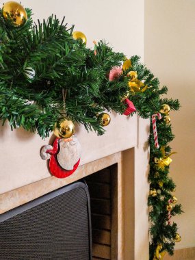 Şömine sahnesi şenlikli bir çelenk, parlayan ışıklar ve süslerle süslenmiş. Noel kartları, tatil blogları ya da kışlık internet siteleri için mükemmel. Sıcaklığı ve bayram neşesini çağrıştırıyor.