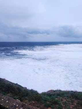Kasvetli bir gökyüzünün altında güçlü dalgaların kıyıya çarptığı dramatik bir okyanus manzarası. Güç, esneklik ve doğal güzelliği çağrıştırıyor. Seyahat, hava durumu, duygusal kavramlar için mükemmel..