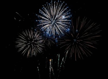 Karanlık bir gece gökyüzüne karşı muhteşem havai fişek gösterisi. Birden fazla renkli patlama ve parlak izler, kutlamalar, tatiller ve etkinlik promosyonu için ideal dinamik ve şenlikli bir sahne yaratır..