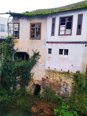 ALCOBACA, PORTUGAL - 08 Ocak 2024: bitkilerle kaplı harap bir bina. Camlar kırılmış. Çürümeyi, terk edilmeyi ya da şehir keşfi temalarını gösterebilir.