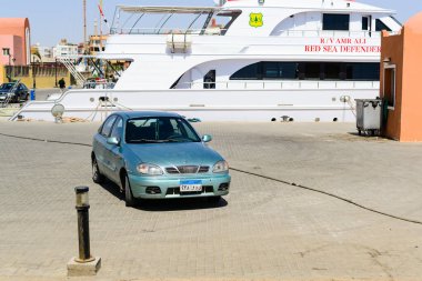 SHARM EL SHEIKH, EGYPT - HAZİRAN 01, 2017: büyük bir yatın yakınındaki bir marinada park edilmiş mavi araba. Seyahat, ulaşım veya yaşam tarzı yayınları için düzenleyici resim.
