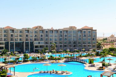 SHARM EL SHEIKH, EGYPT - Haziran 04, 2017: Havuzu, bereketli peyzajı ve palmiye ağaçları olan bir otel. Turistler rahatlar ve tatilin tadını çıkarırlar. Arka planda cami ve yel değirmenleri. Düzenleyici kullanımı.