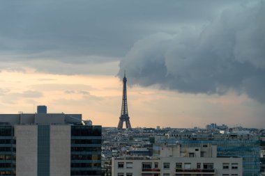 Eiffel Kulesi 'nin uzak bir görüntüsü bulutlu bir gökyüzü ve şehrin üzerine fırtına geliyor.