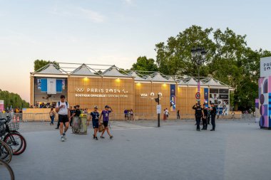 Paris, Fransa - 10 Ağustos 2024: Akşam karanlığında Şanzelize 'deki Olimpik Açılır Butik önünde ziyaretçiler ve polis