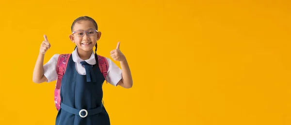 Back to school banner idea concept, Happy asian school girl in uniform with show thumbs up for good, isolated on yellow background with Clipping paths for design work empty free space