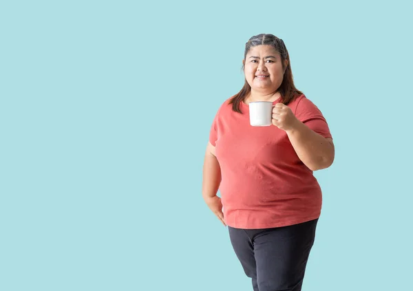 Fat woman asian happy smiling holding a mug, isolated on blue background