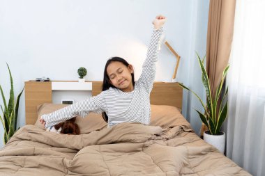 Uyan konsept, mutlu Asyalı genç Taylandlı kız sabahları yatağında uzanıyor, beyaz pijama giyiyor.