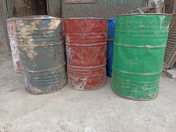Dükkanın önünde birkaç tane kirli mavi, yeşil ve turuncu varil var.