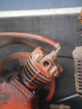 Tozla kirlenmiş turuncu bir kompresörün parçası.