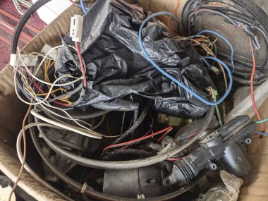 Kirli bir karton kutuda kullanılmış kablolar yığını. Kullanılmayan küçük kablo.