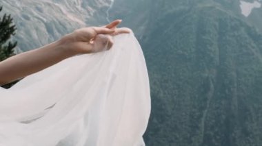 Bir kadının eli dağların arka planında bir erkeğin eline uzanır.