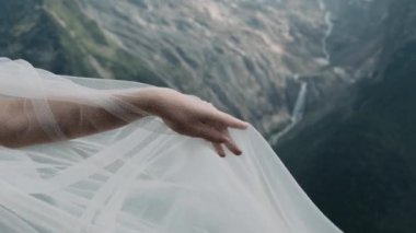 Bir kadının eli dağların arka planında bir erkeğin eline uzanır.