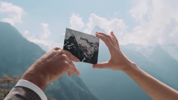 山の背景に山を持つカードを保持する男性と女性の手 — ストック動画