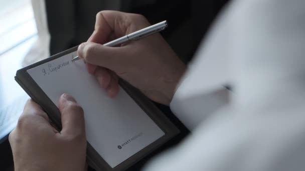 男はペンでメモ帳に書いている — ストック動画
