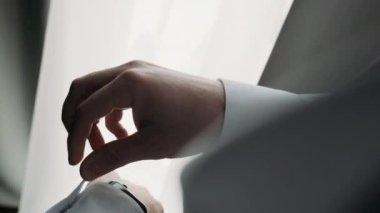  İş adamı beyaz gömleğin kol düğmelerini ayarlıyor.