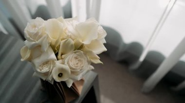 Bir buket beyaz gül masanın üstündeki vazoda duruyor.