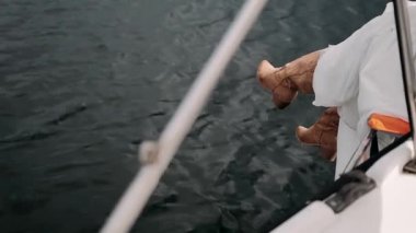 Kahverengi çizmeli sert bacaklar yatın kenarında su manzaralı.