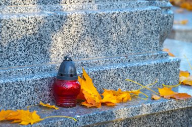 Sonbaharda yapraklı bir mezar ışığı, eski mezarlıkta klasik lambalar.